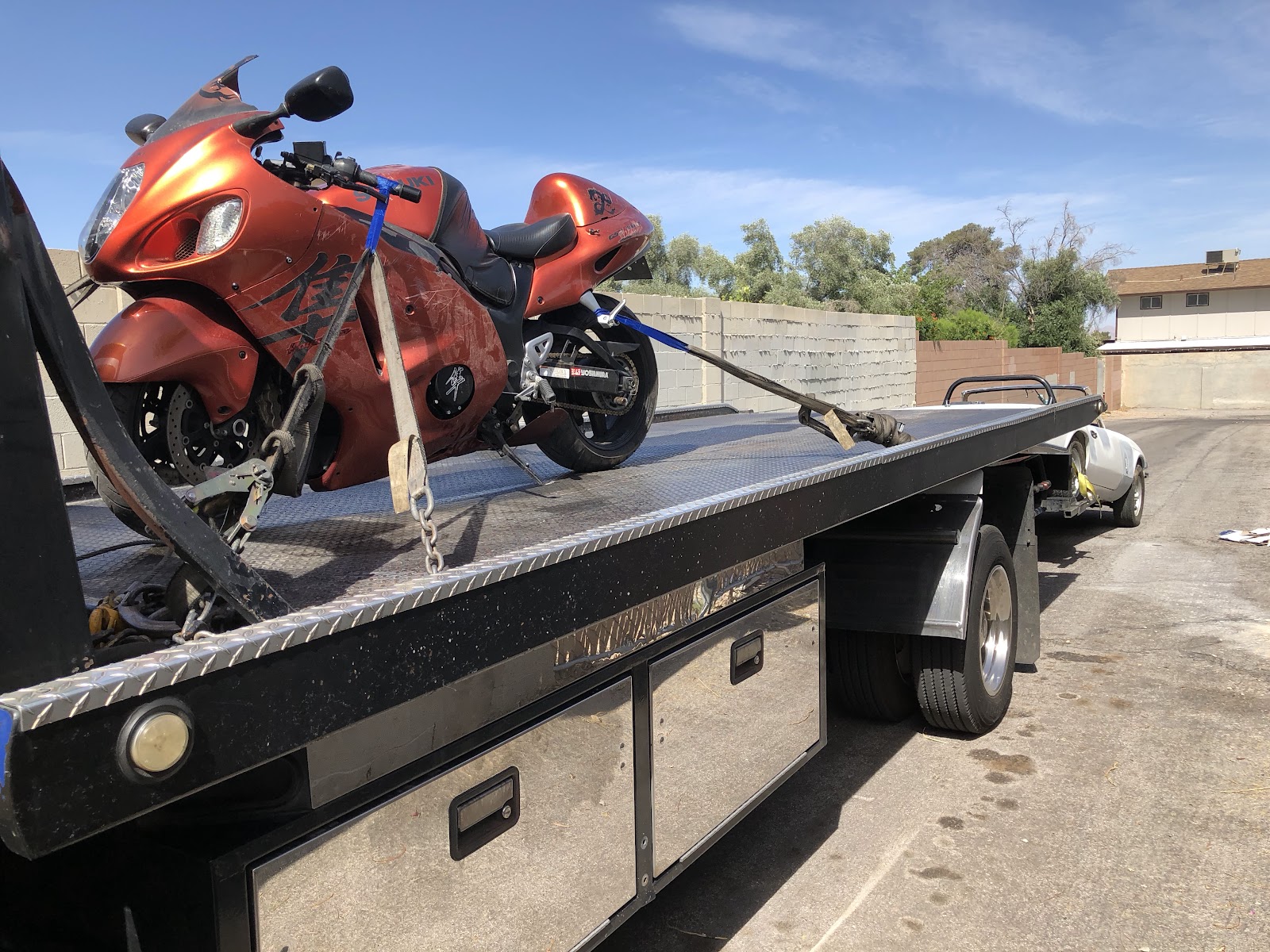 Orange Suzuki Hayabusa motorcycle strapped on a flatbed tow truck