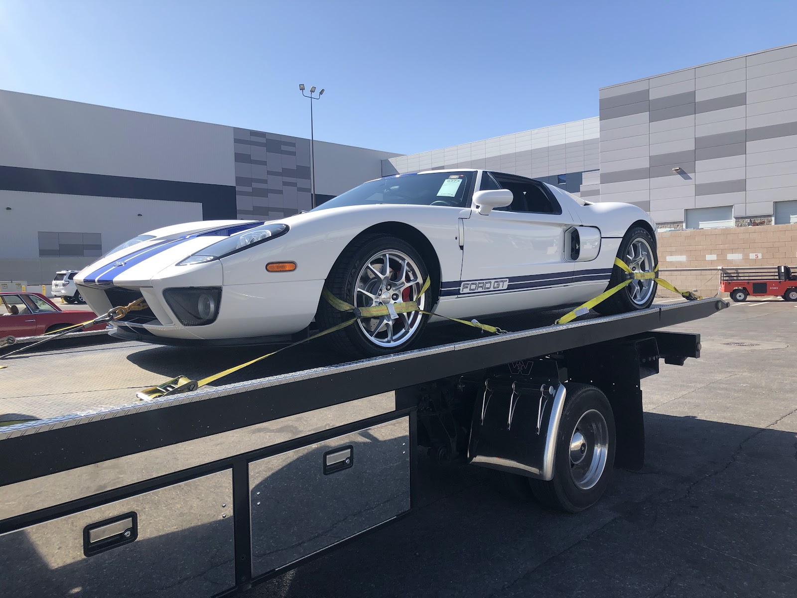 White Ford GT supercar strapped and loaded on a flatbed tow truck